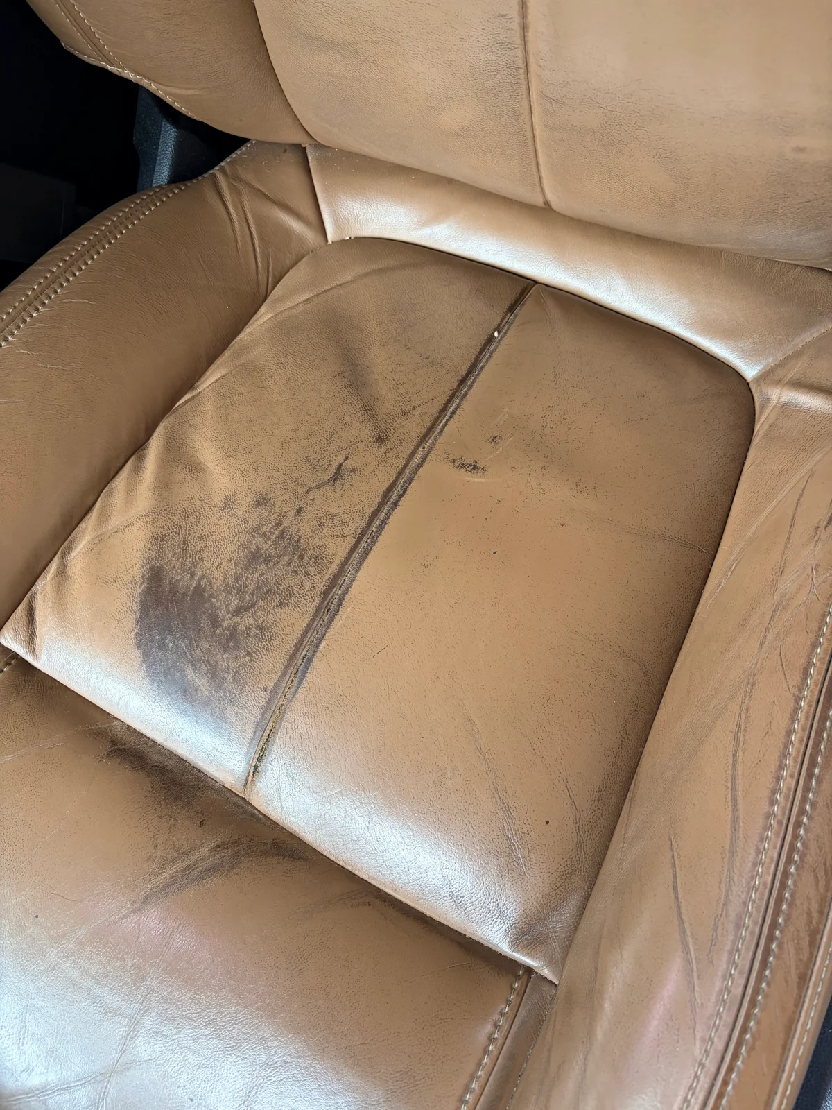 2015 Buick LaCrosse driver's seat cushion before restoration — dark discoloration and contamination visible on the leather surface