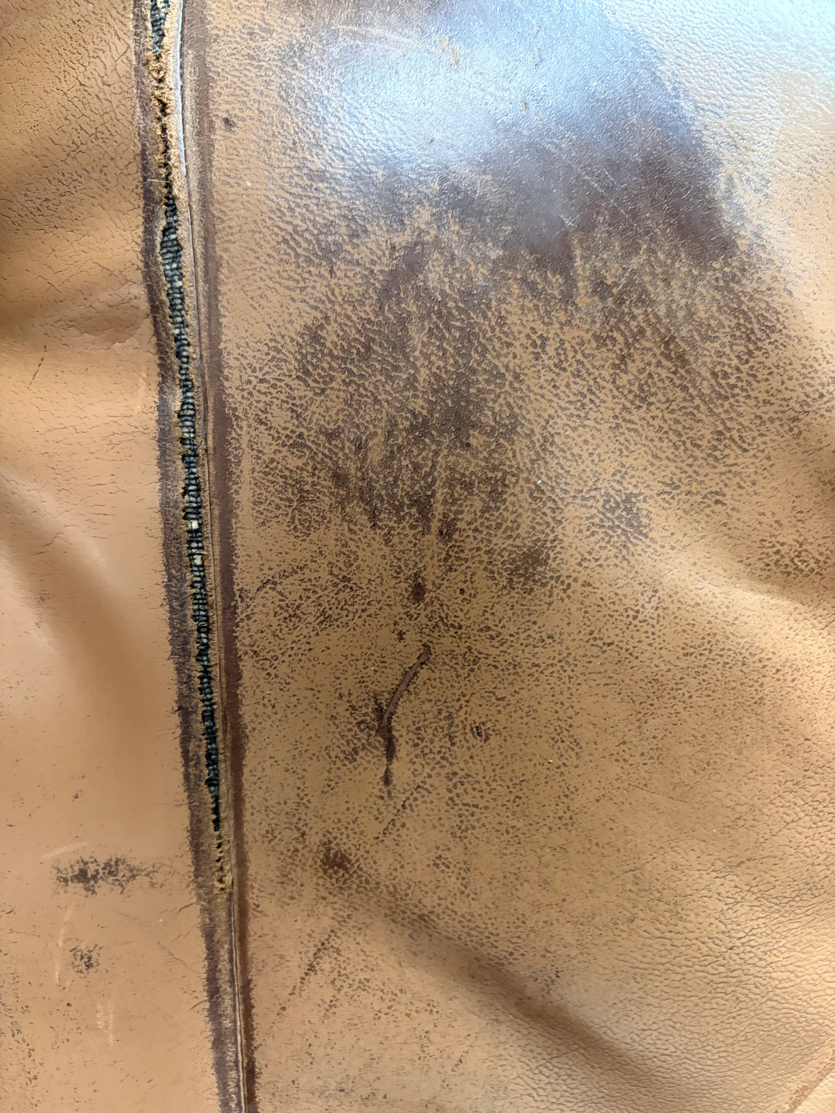 2015 Buick LaCrosse central leather seat panel before restoration — seam tear with padding exposed and surrounding discoloration