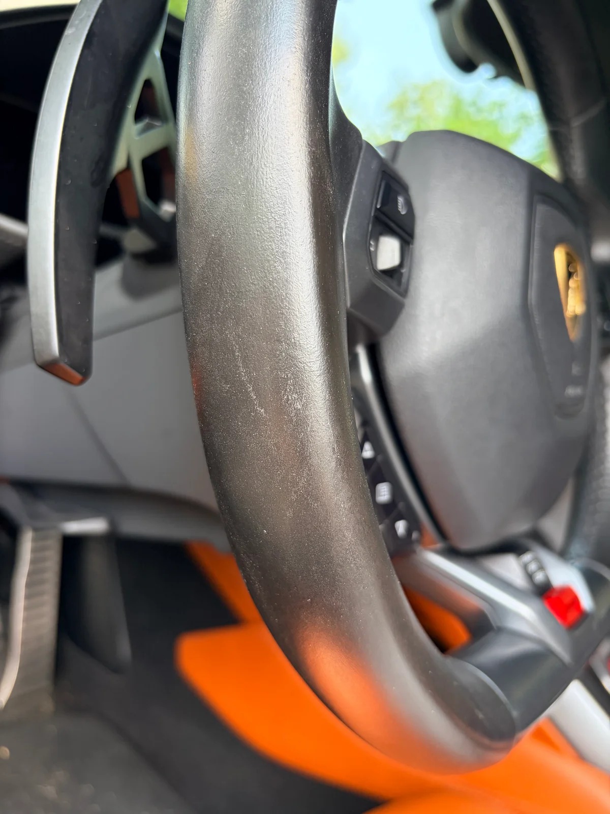 Lamborghini Huracán steering wheel before restoration — uneven sheen and mottled texture from a previous cosmetic refinish