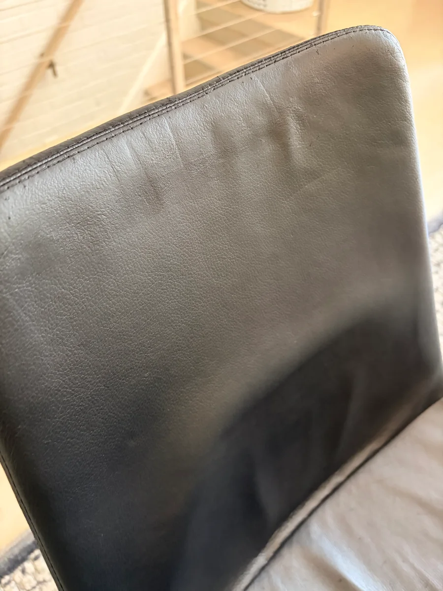 Close-up of a restored black leather chair back with an even surface and finish
