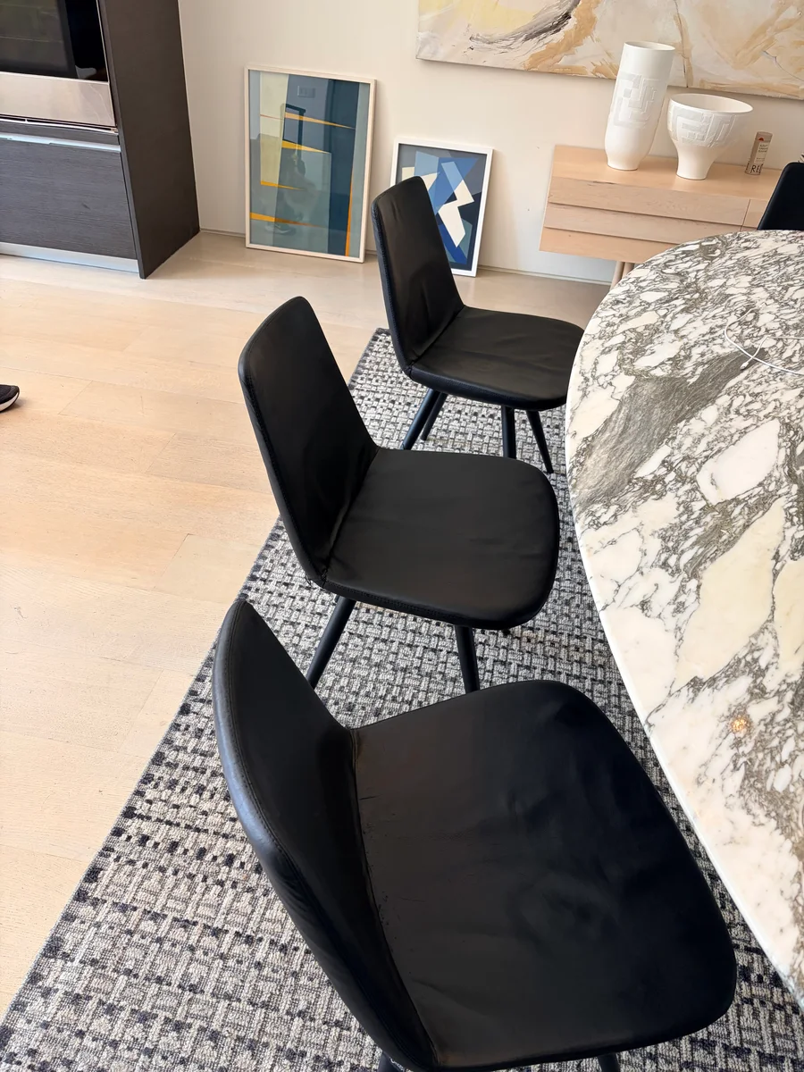 Several black leather dining chairs after cat-scratch restoration in Clinton Hill
