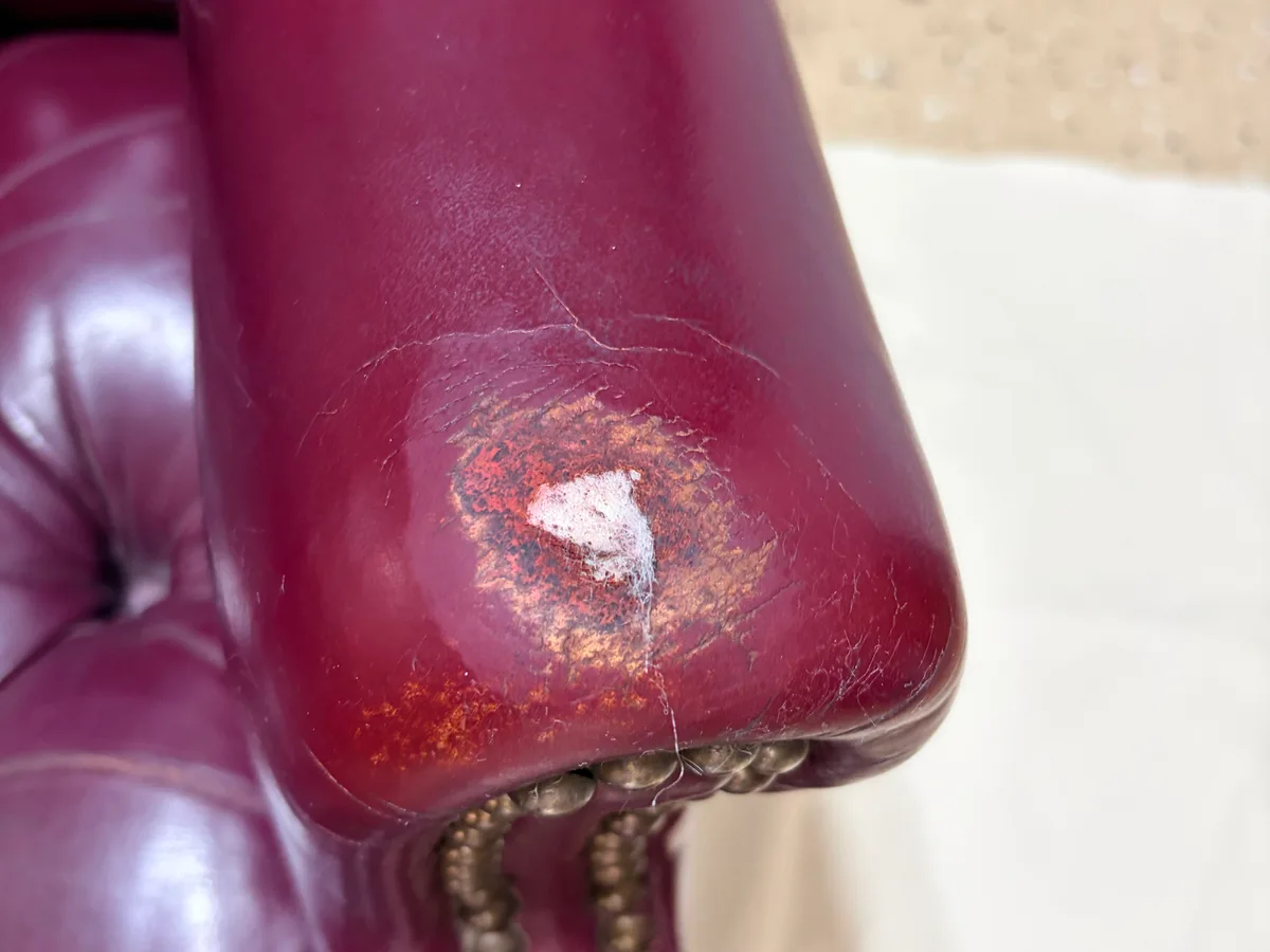 Chesterfield chair second armrest before restoration — worn through area with cracking leather