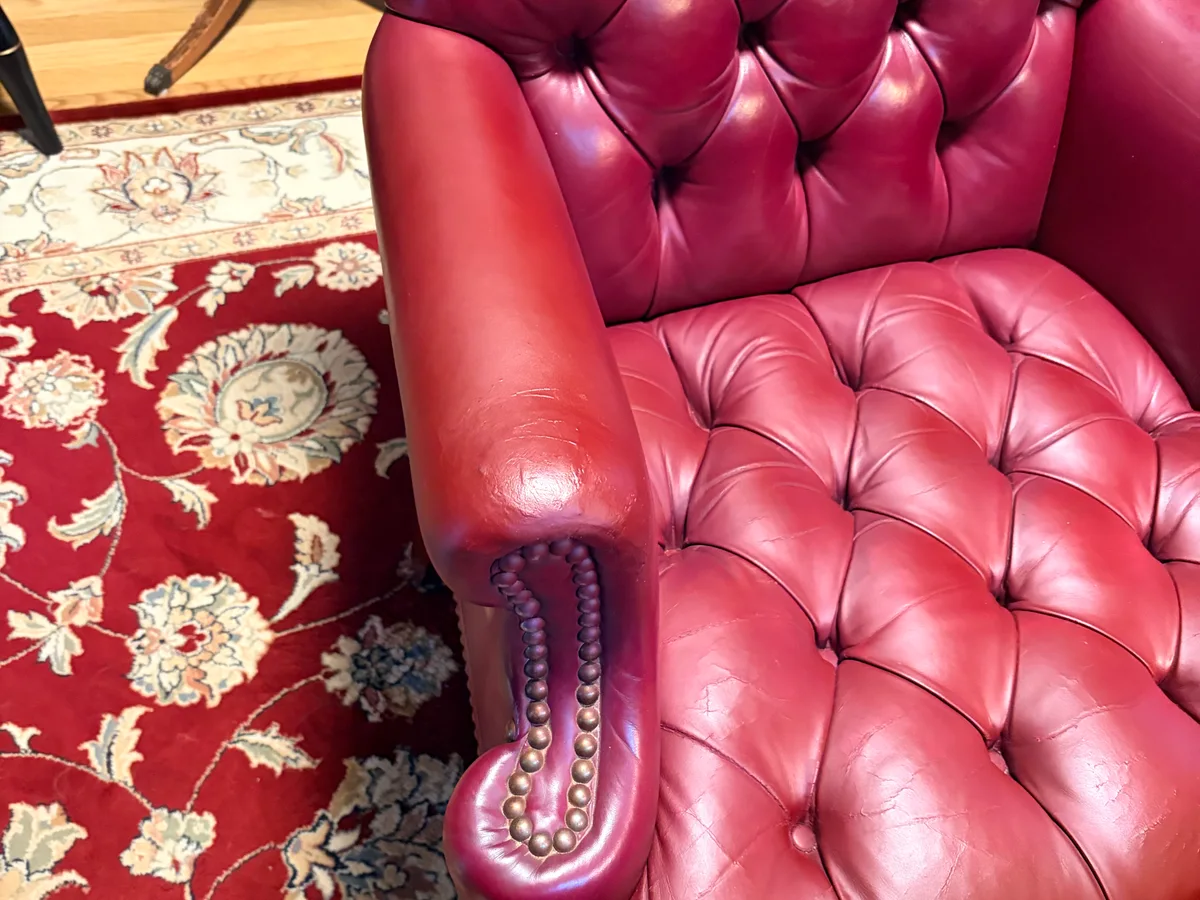Chesterfield chair armrest after leather restoration — repair invisible, color consistent with surrounding leather