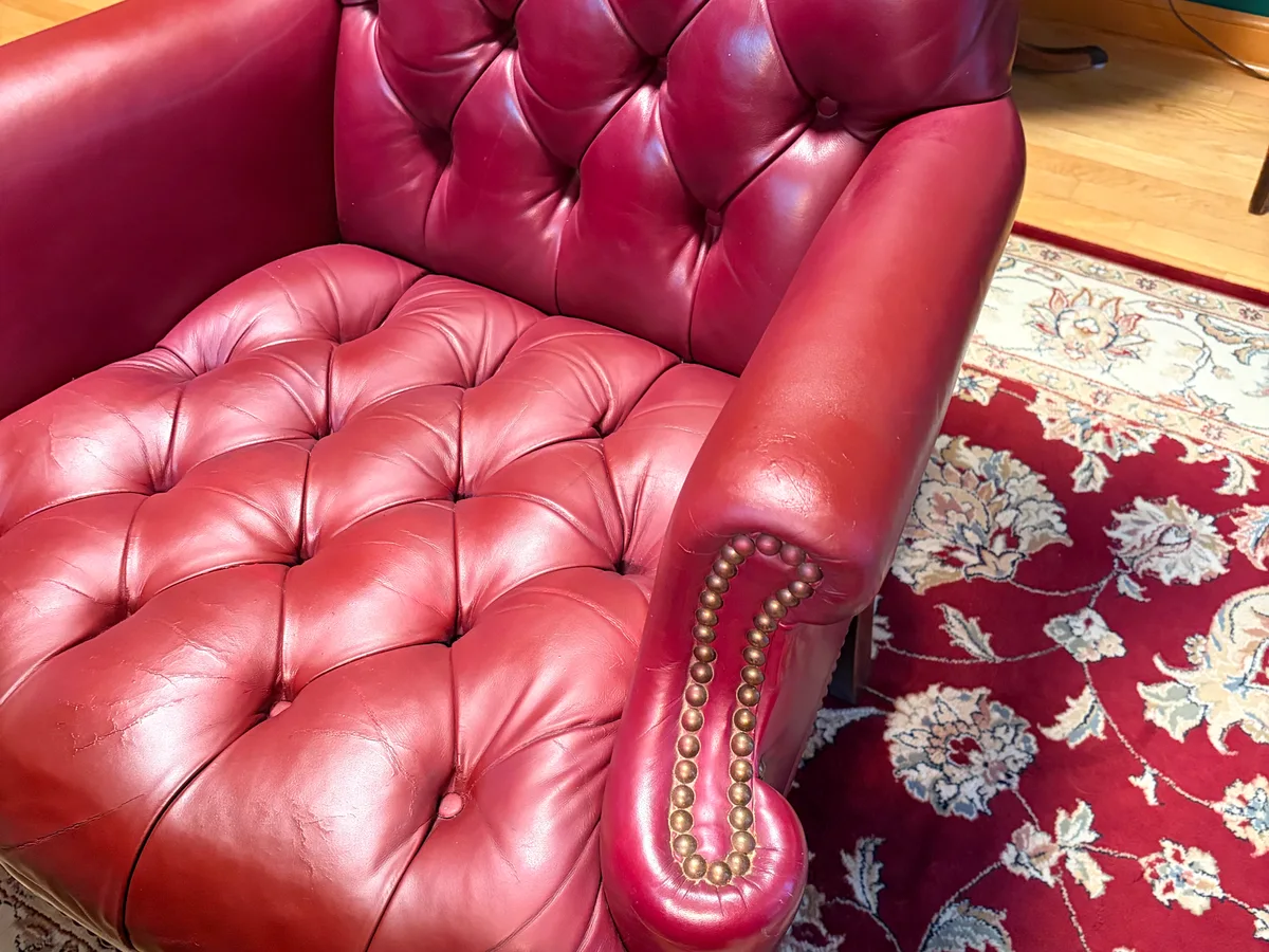 Vintage Chesterfield chair leather detail after restoration — tufted surface and arm showing consistent color