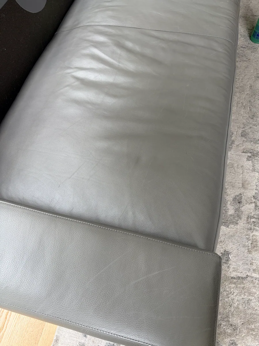 Dog scratches across the gray leather sofa seat and front rail before restoration