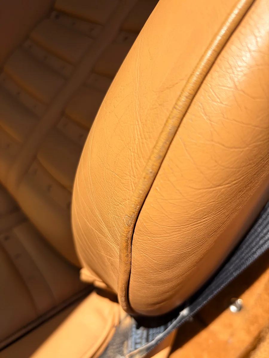 Ferrari 360 Modena seat bolster before restoration — cracking leather and worn piping seam on beige Cuoio leather
