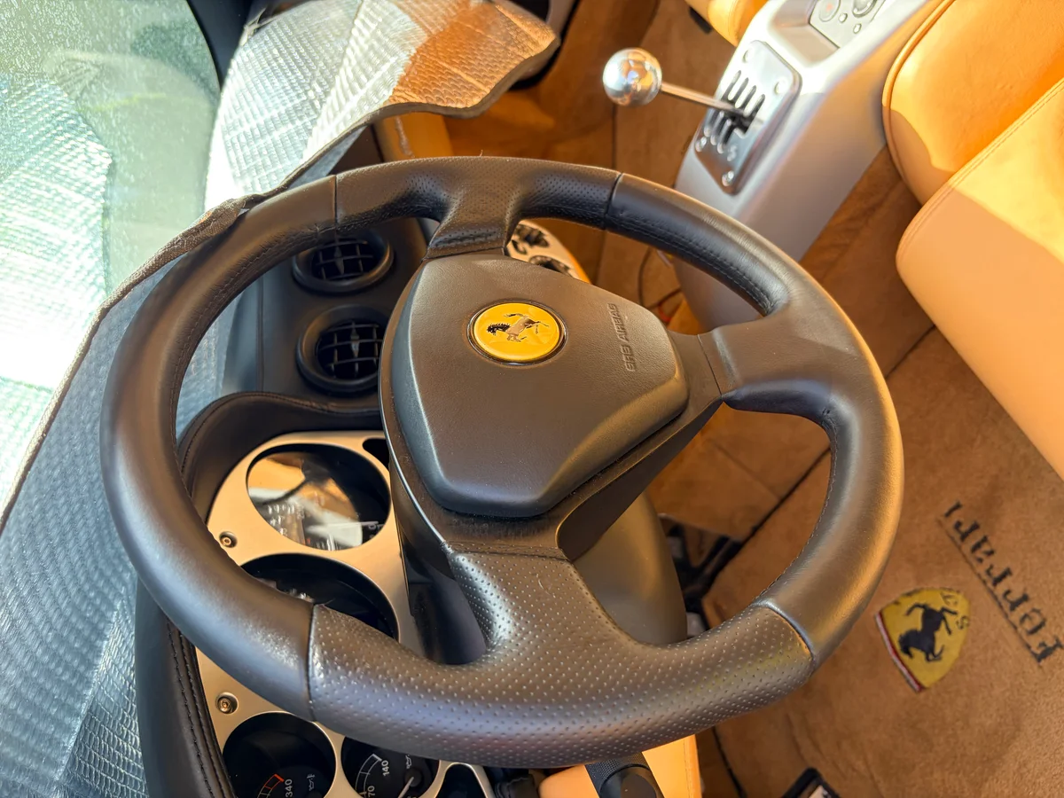 Ferrari 360 Modena cockpit after restoration — steering wheel leather restored to uniform color, Ferrari prancing horse emblem visible