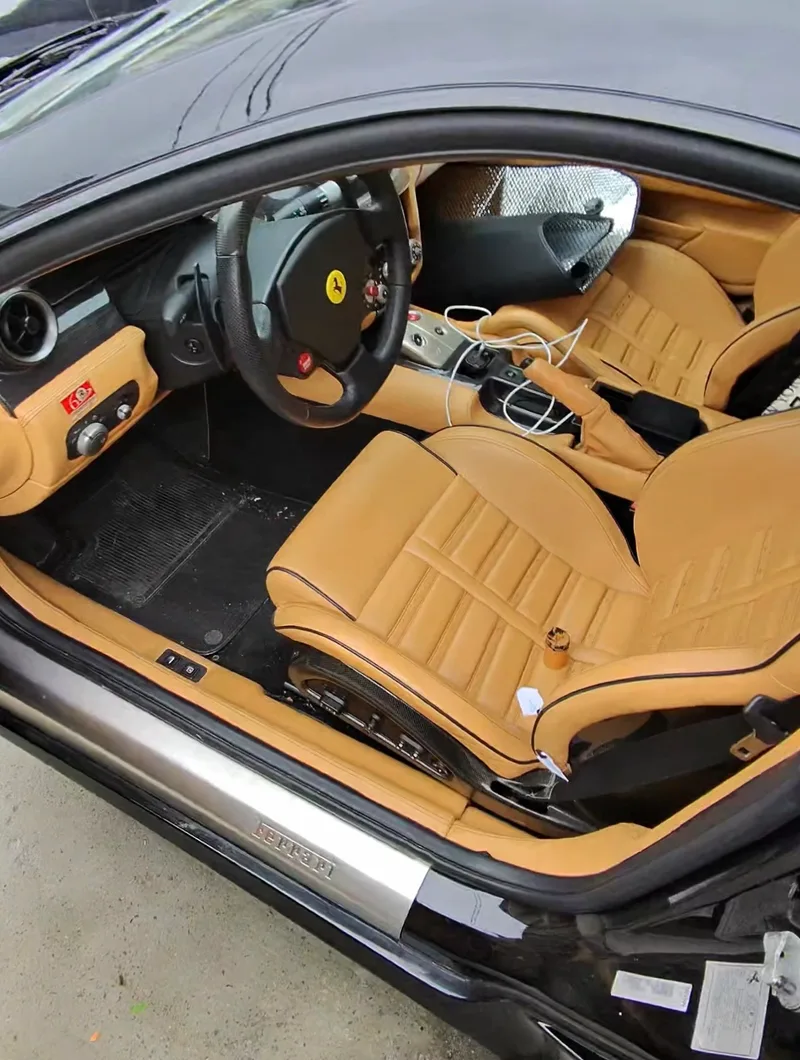 Ferrari 599 GTB Fiorano beige interior before leather seat repair — driver seat and cockpit overview