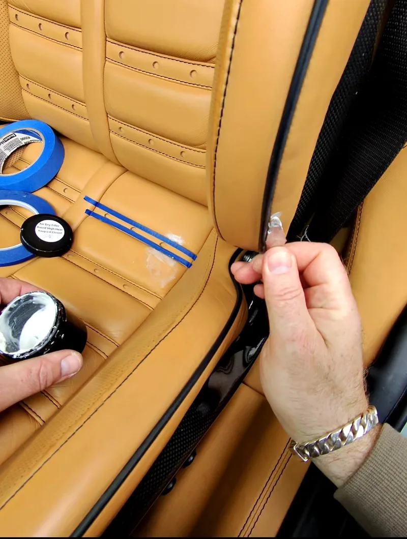 Ferrari 599 GTB seat bolster leather repair — air dry filler and masking tape applied to damaged area
