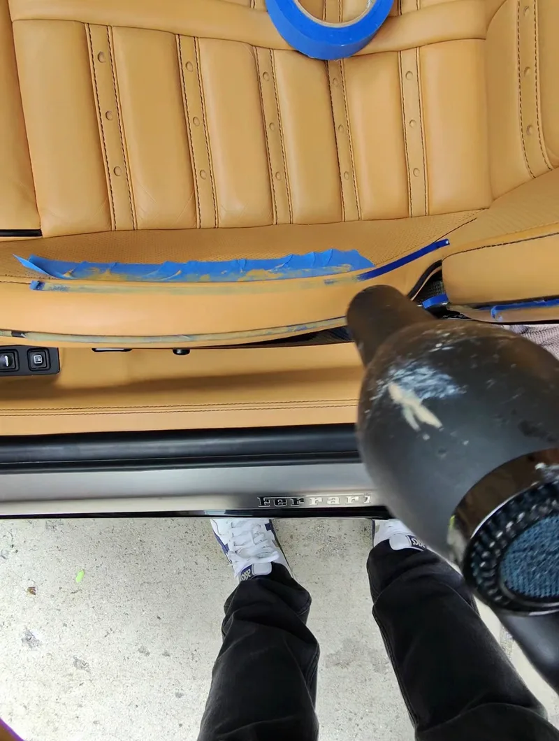 Ferrari 599 GTB seat leather repair heat curing — heat gun used to cure filler compound, Ferrari door sill visible