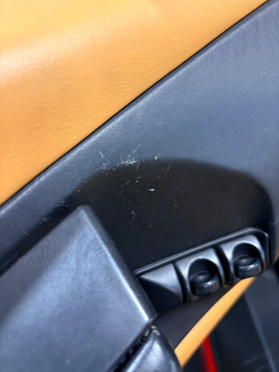 Ferrari F355 door card before restoration — light scratches and scuff marks near the window switch panel