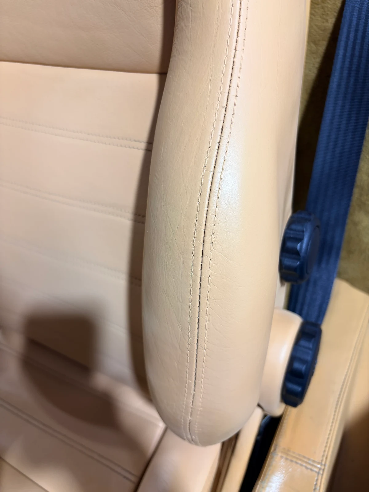 Ferrari F355 driver's seat bolster after restoration — surface corrected and color matched to the surrounding tan leather, natural texture retained