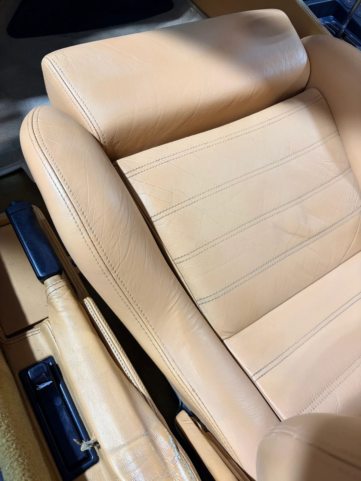 Ferrari F355 seat surface detail after restoration — tan leather with age-appropriate texture and consistent tone