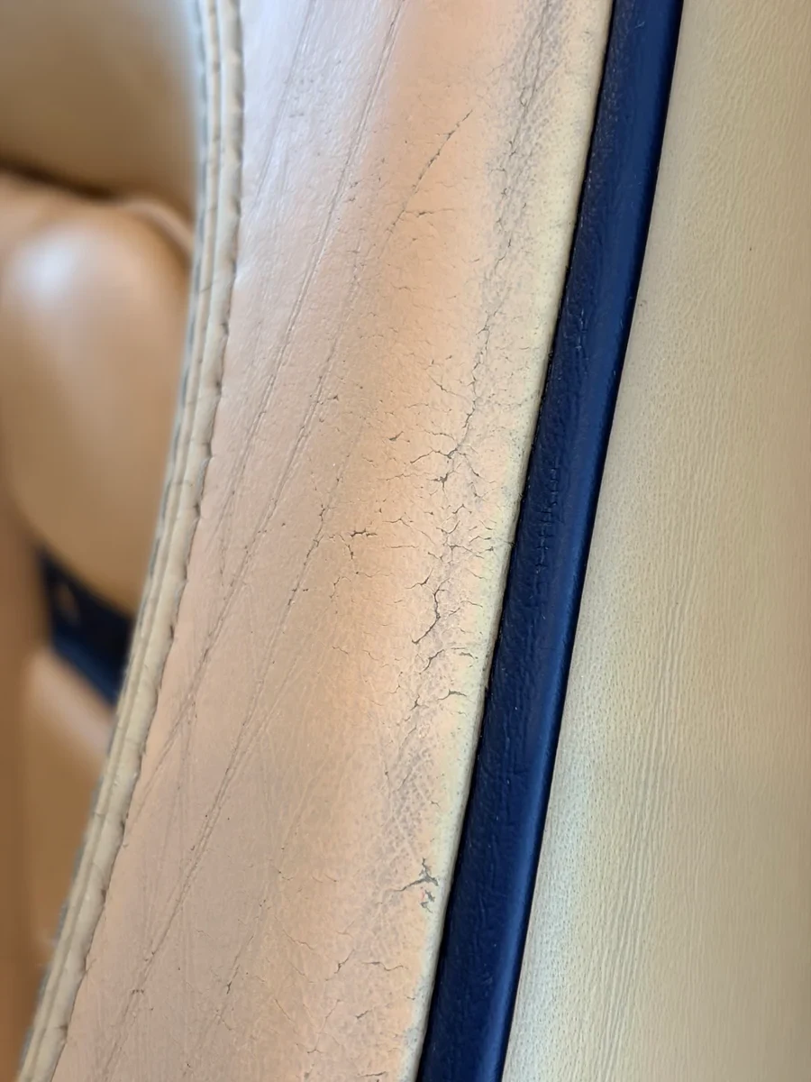 Ferrari F430 Spider seat top edge before restoration — surface cracking along the seam line, black piping visible with wear