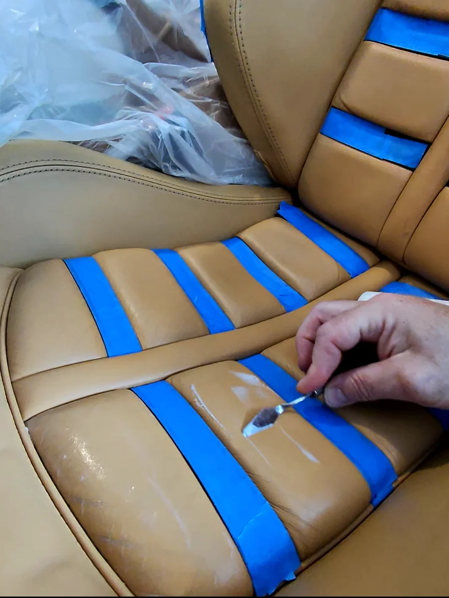 Ferrari F430 Daytona seat with blue painter's tape masking every black leather insert before color application
