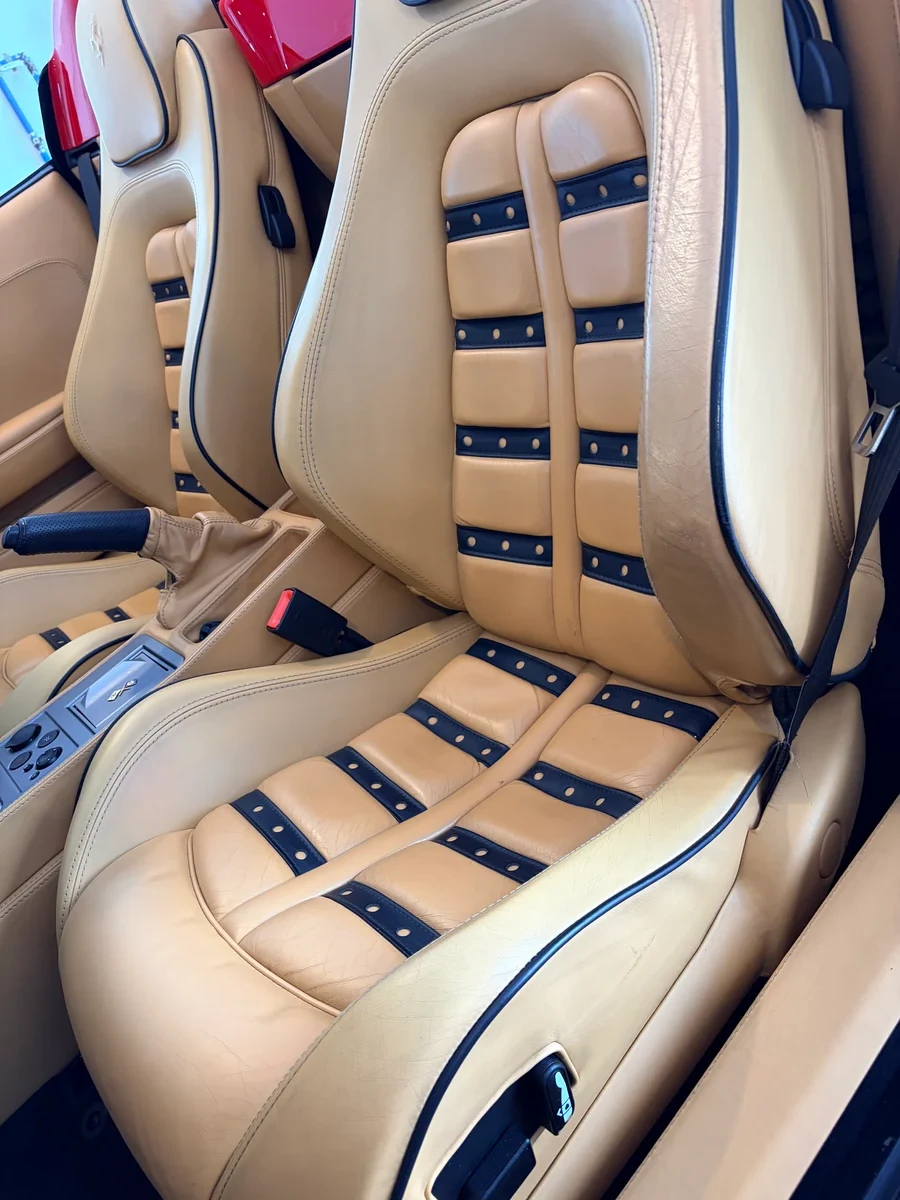 Ferrari F430 Daytona seats — both front seats showing Cuoio leather with black leather inserts and characteristic horizontal strap pattern