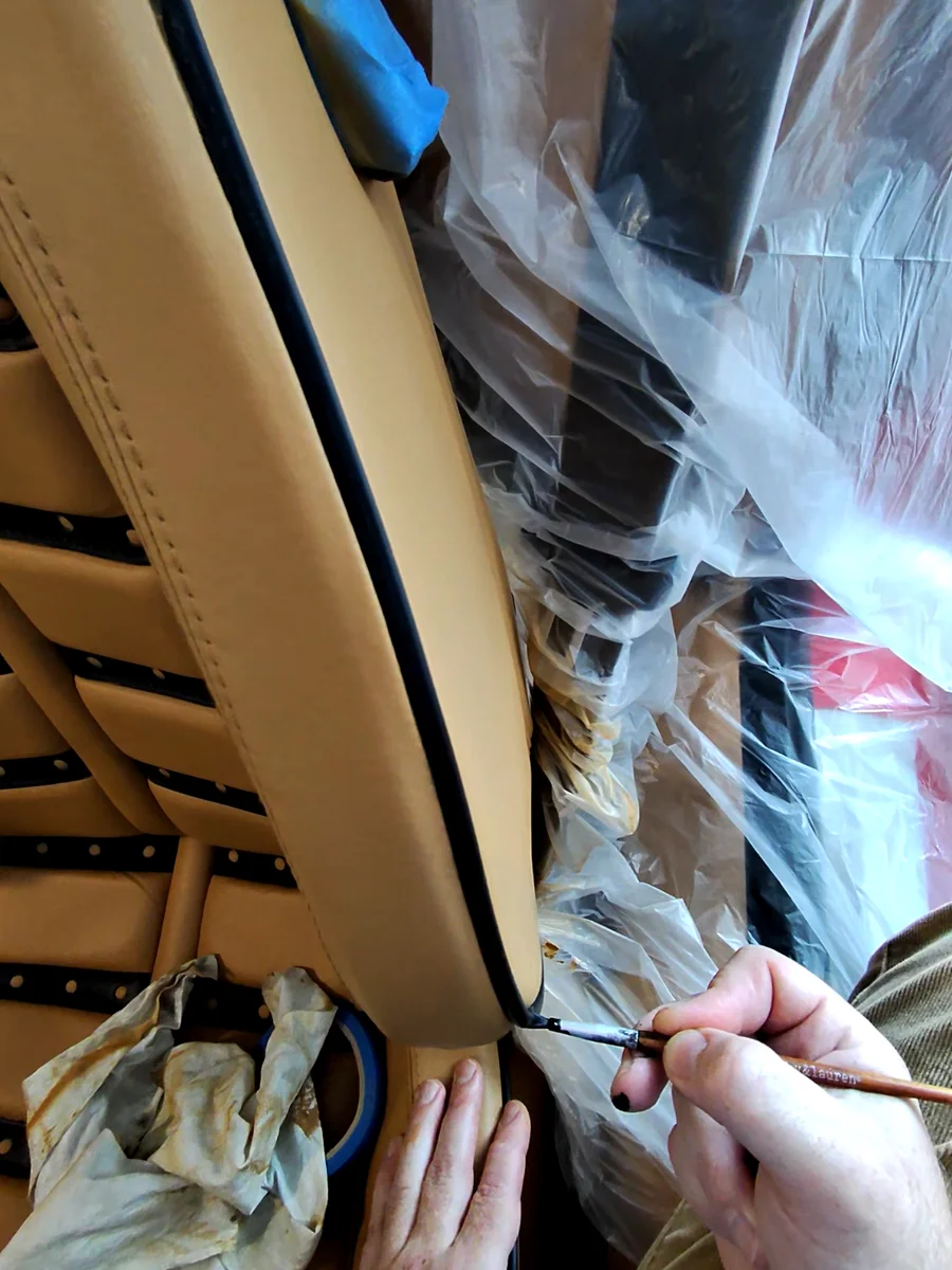 Fine artist's brush used to restore black piping along Ferrari F430 seat edge — detail hand work