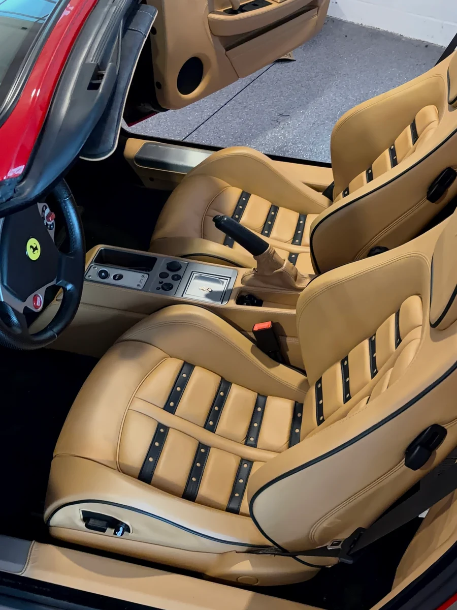 2007 Ferrari F430 Spider interior from outside the car — both restored Daytona seats visible, Cuoio leather and black inserts showing full interior