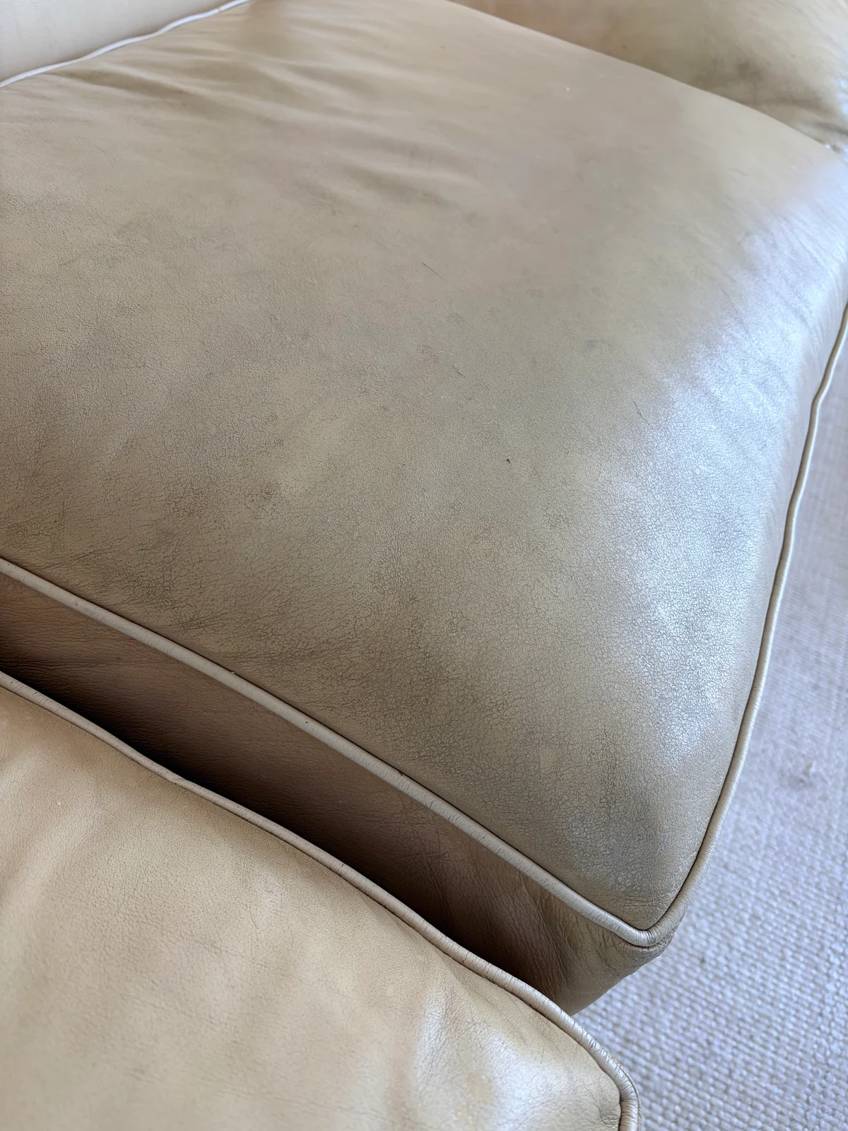 Close-up of UV-faded leather sofa cushion before restoration — color loss, dirt accumulation, and finish degradation visible