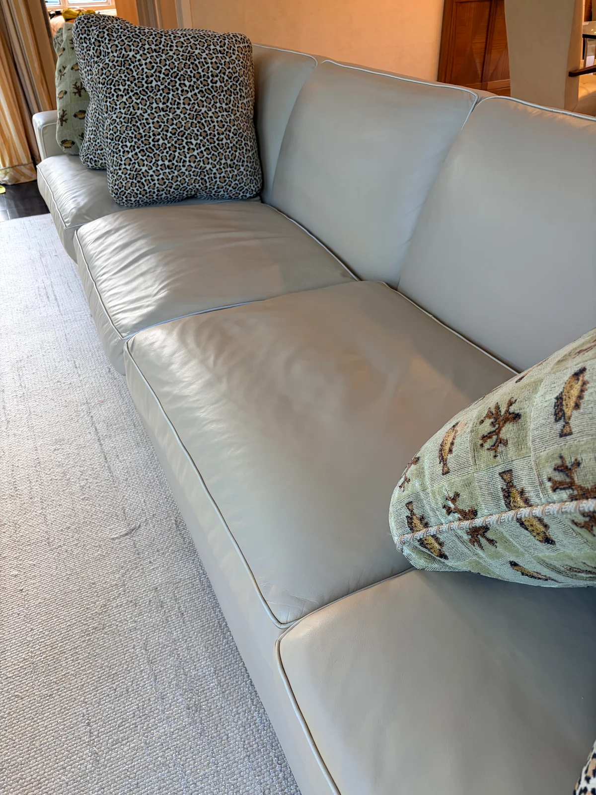 Luxury leather sofa close-up after professional color restoration in New York — custom color applied, white contrast piping preserved along every panel edge