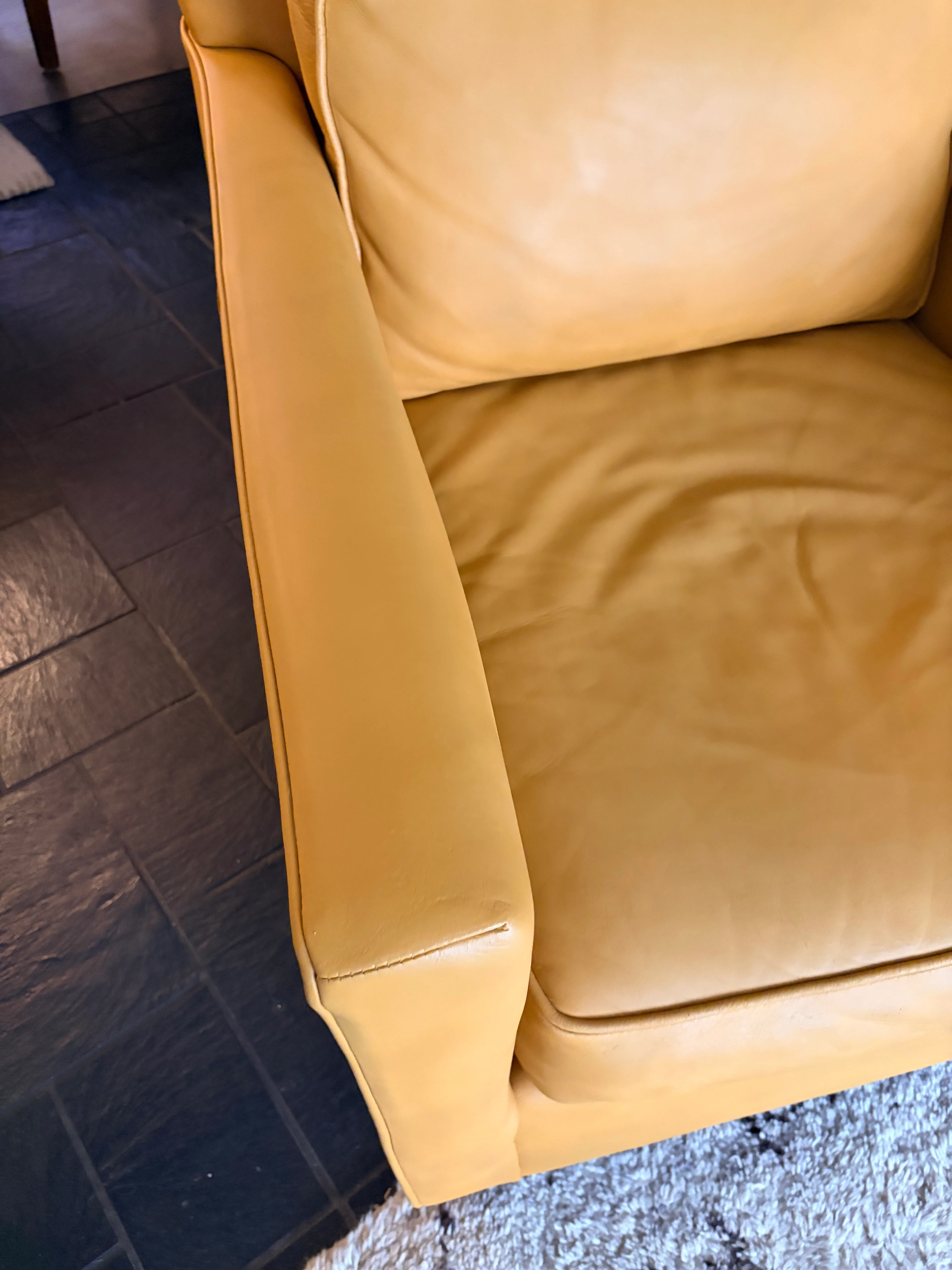 Mitchell Gold Hunter leather chair arm and seat area after restoration — smooth even Saffron color where armrest cracking previously existed
