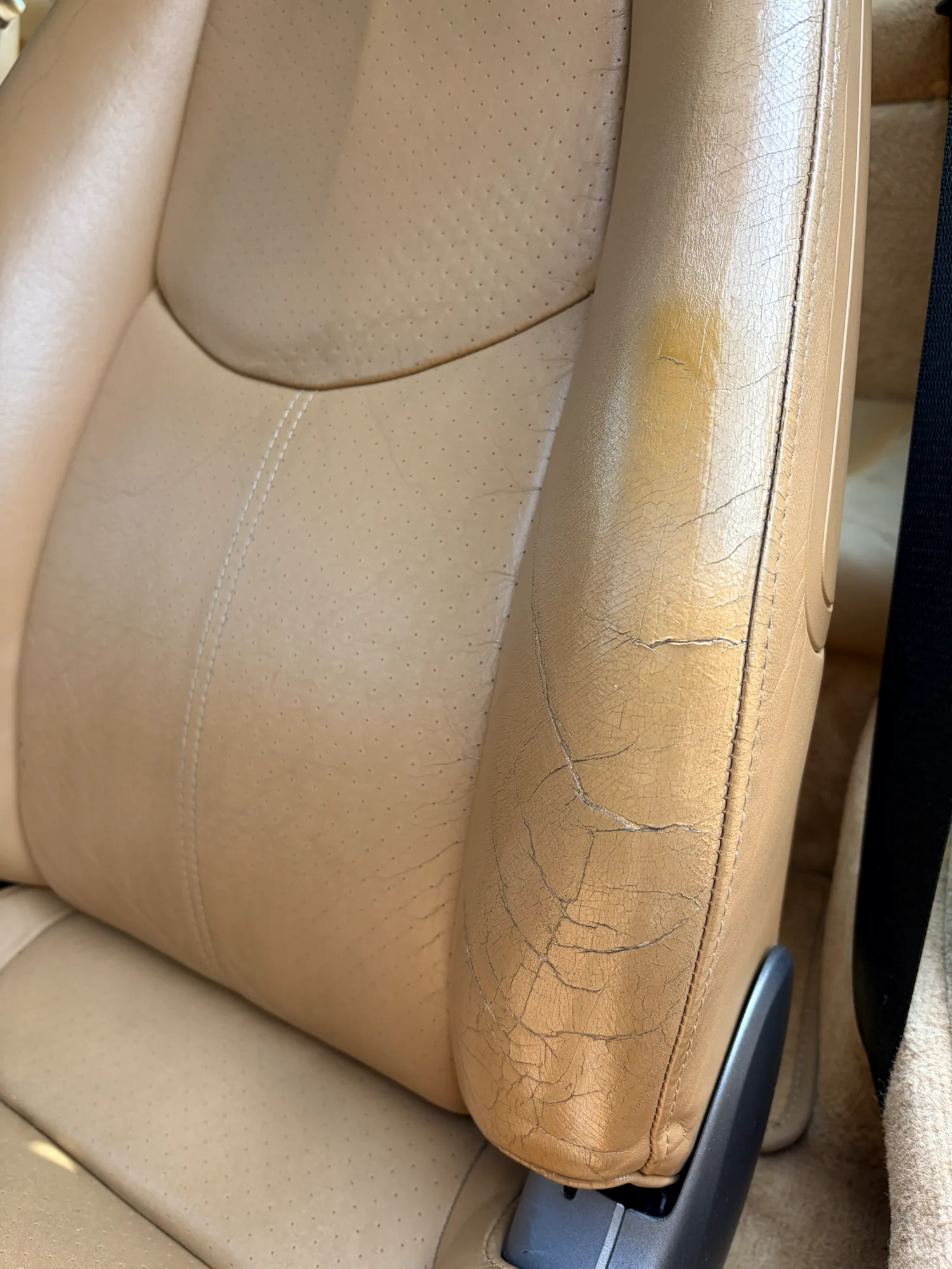 Deep cracks and an incorrect greenish previous repair on the outer seat bolster before restoration