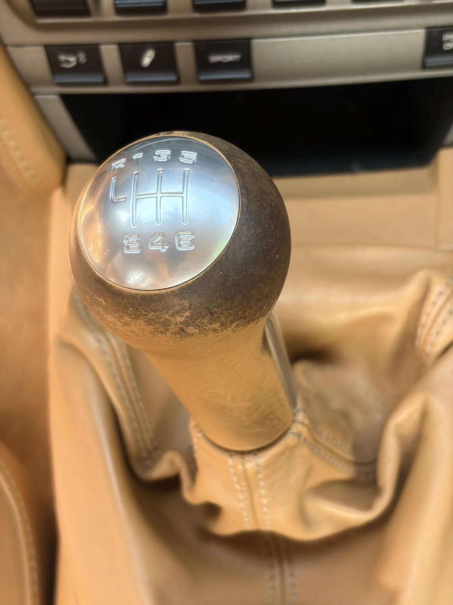 Porsche manual gear shifter before restoration with extensive dark finish loss on the tan leather