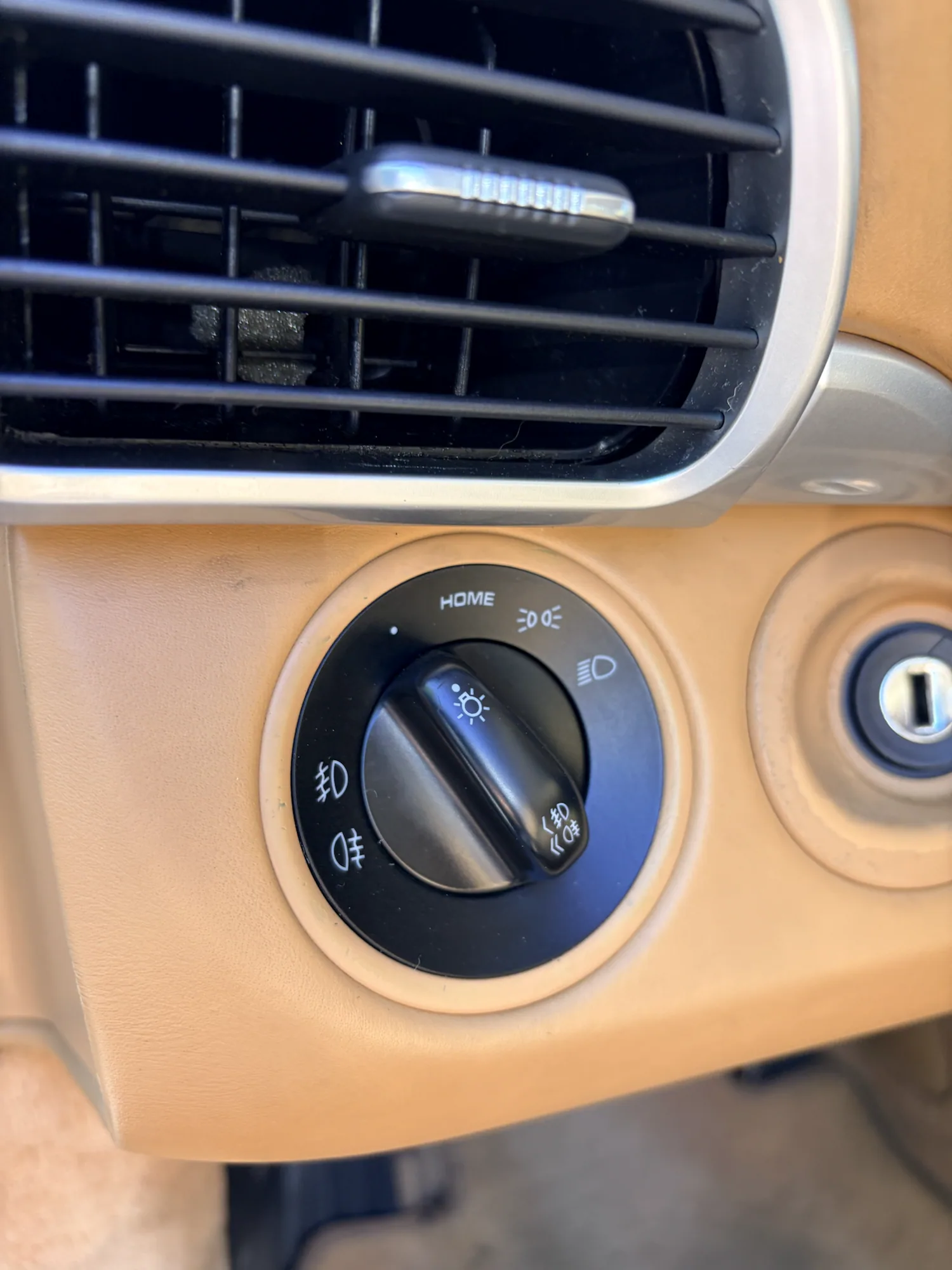 Porsche headlight control surround after localized tan finish restoration