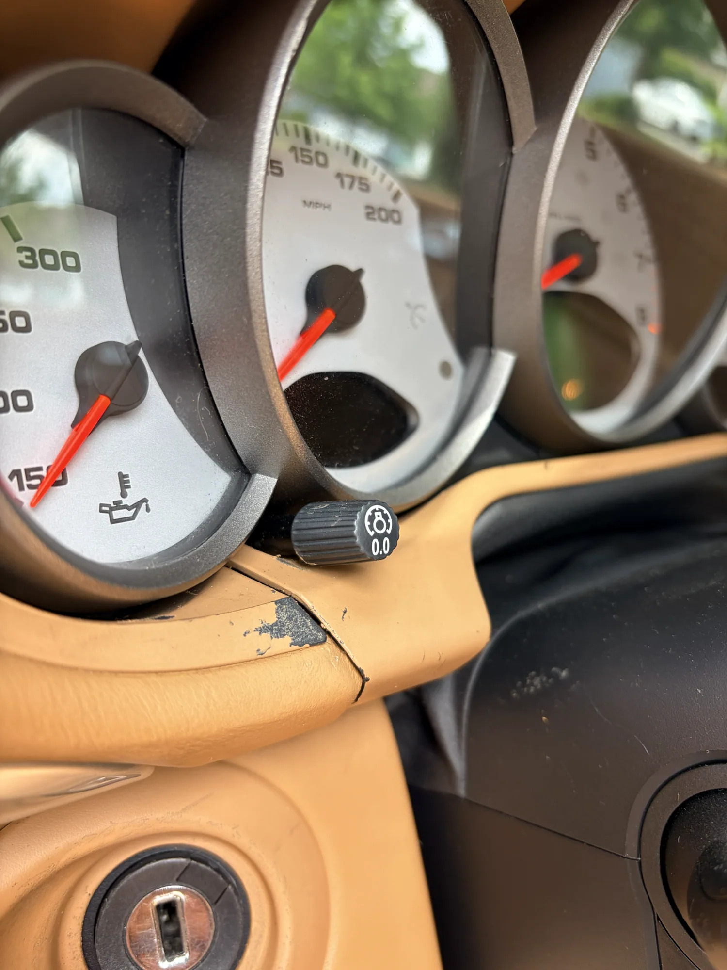 Finish loss exposing a dark layer on the tan instrument cluster surround before repair