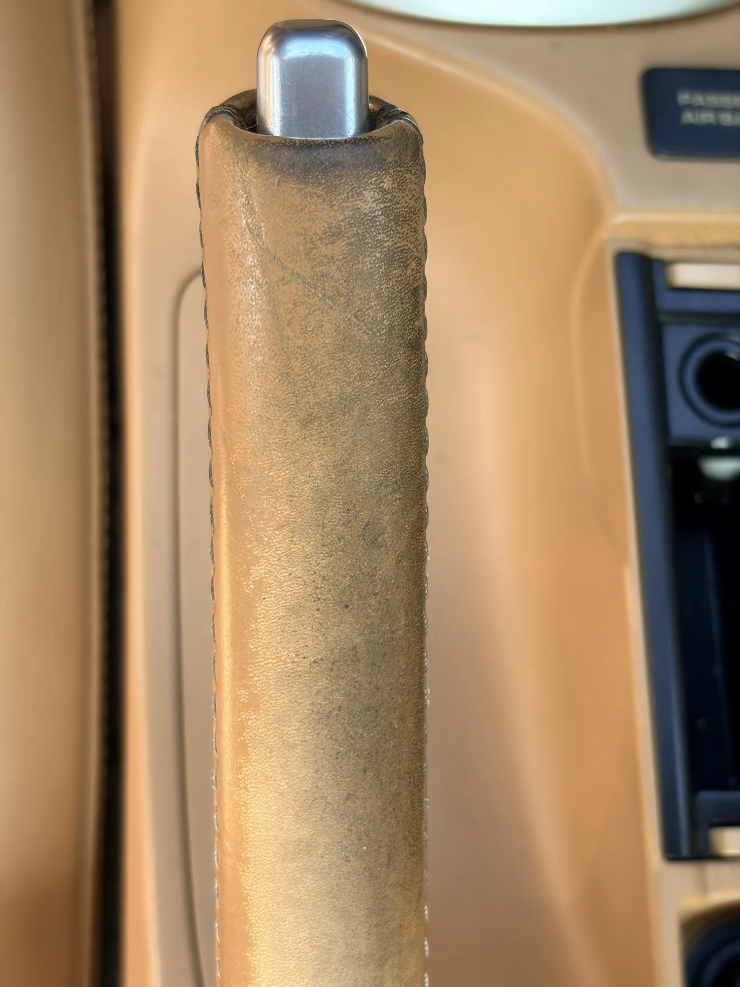 Porsche parking brake and center-console ashtray cover before restoration, with dark wear across the leather grip