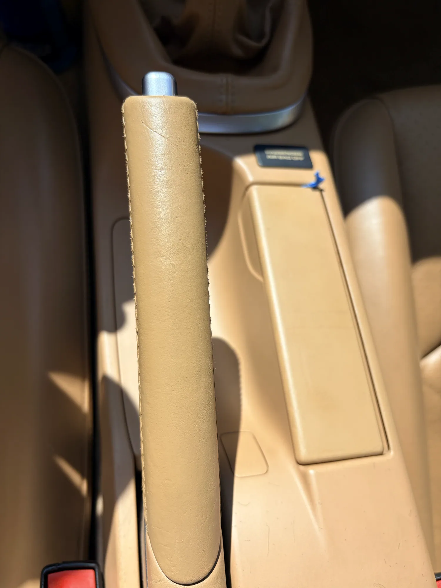Tan Porsche parking brake and center-console ashtray cover after finish and color restoration