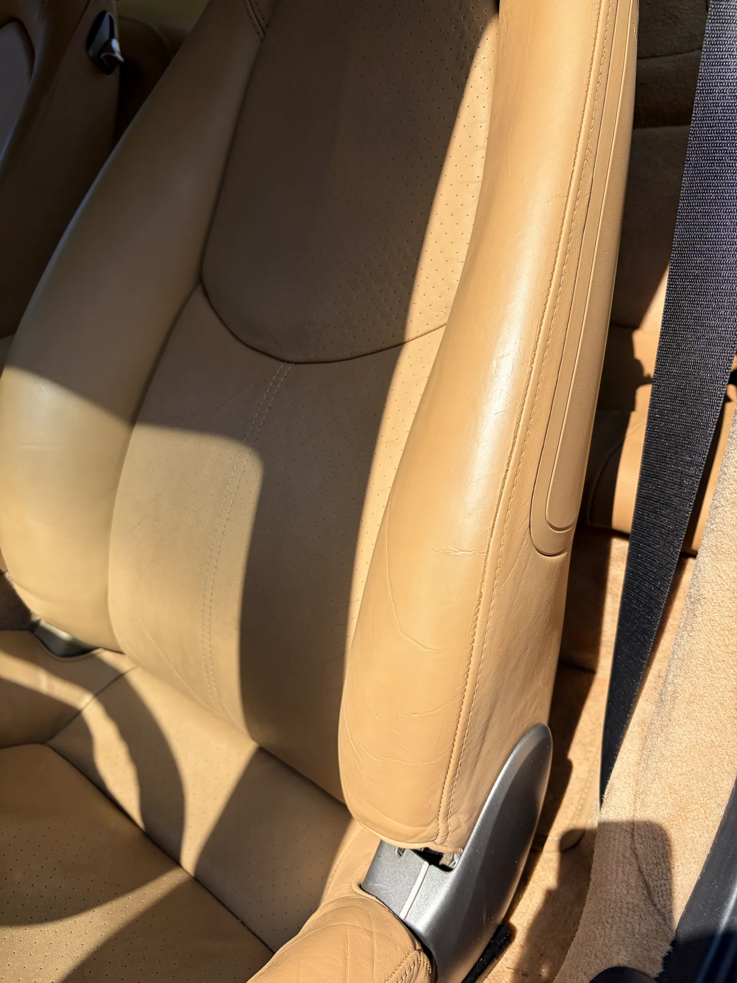 Tan Porsche leather seat bolster after crack repair and custom color refinishing with natural creases retained
