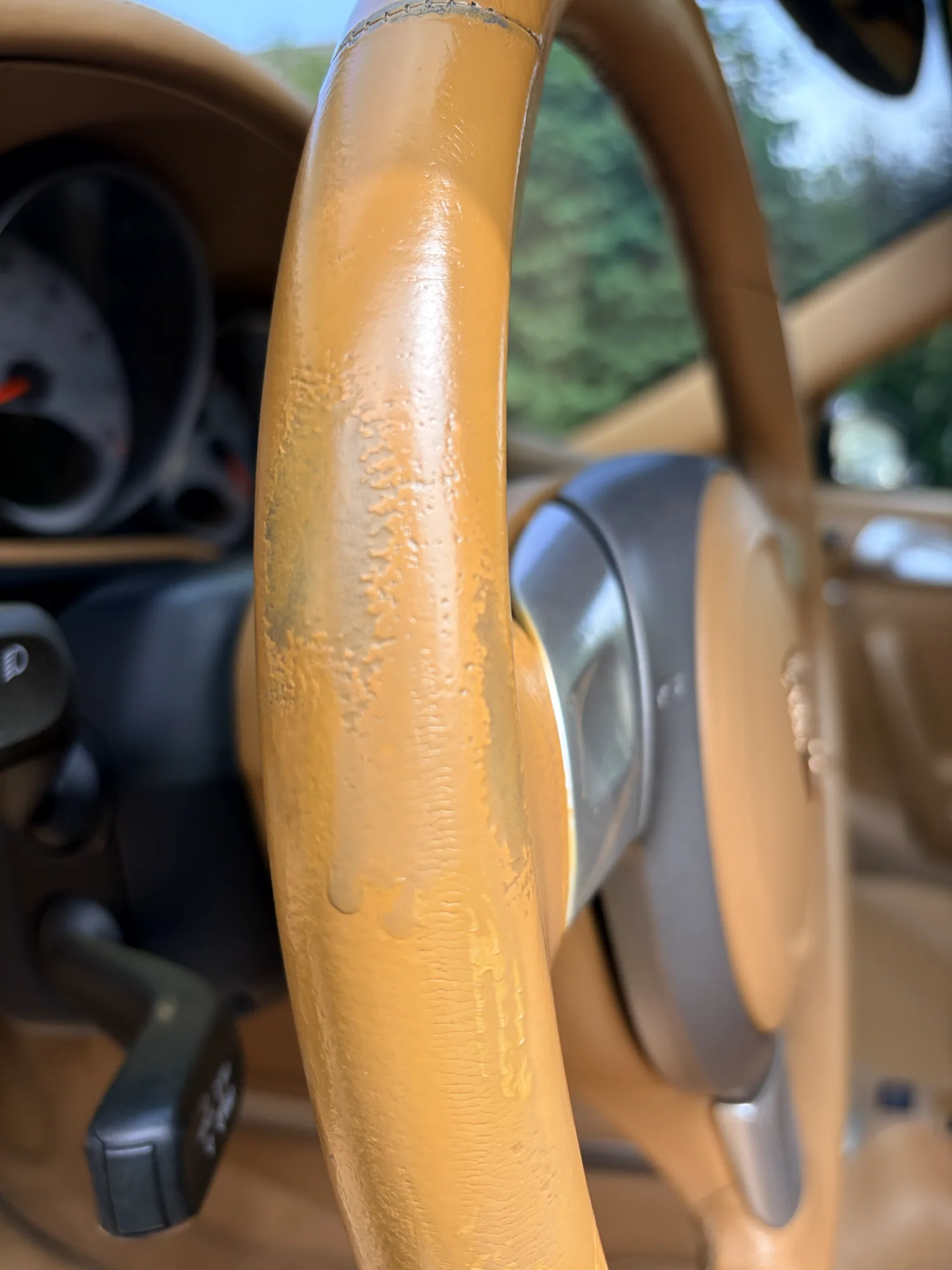 Porsche steering wheel before corrective restoration with uneven color, coating buildup, runs, and exposed wear