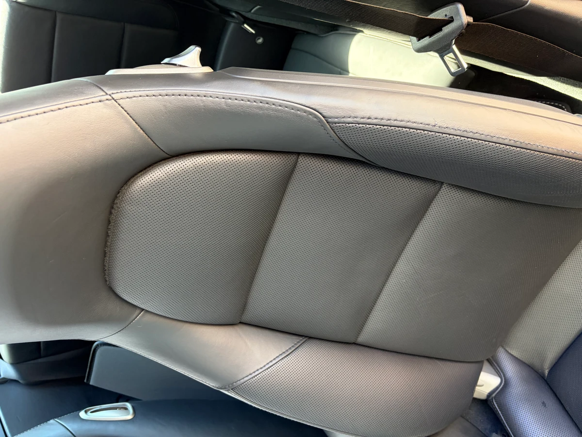 Porsche 911 Targa 4 driver seat before restoration — black perforated leather showing wear and color inconsistency across the seat face and bolster area