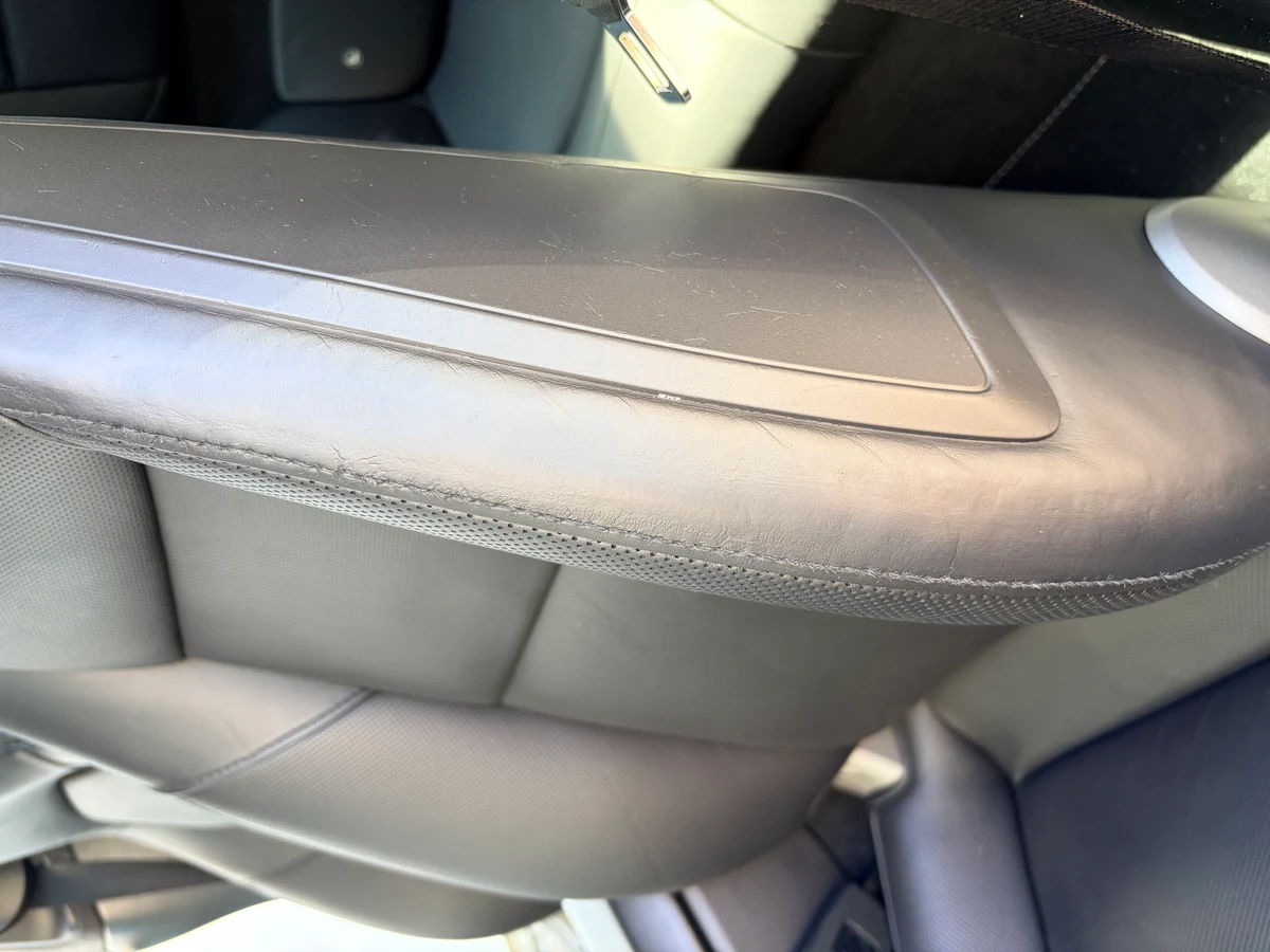 Porsche 911 Targa 4 driver seat outer bolster before restoration — surface finish deteriorated with cracking and color loss along the lateral bolster edge