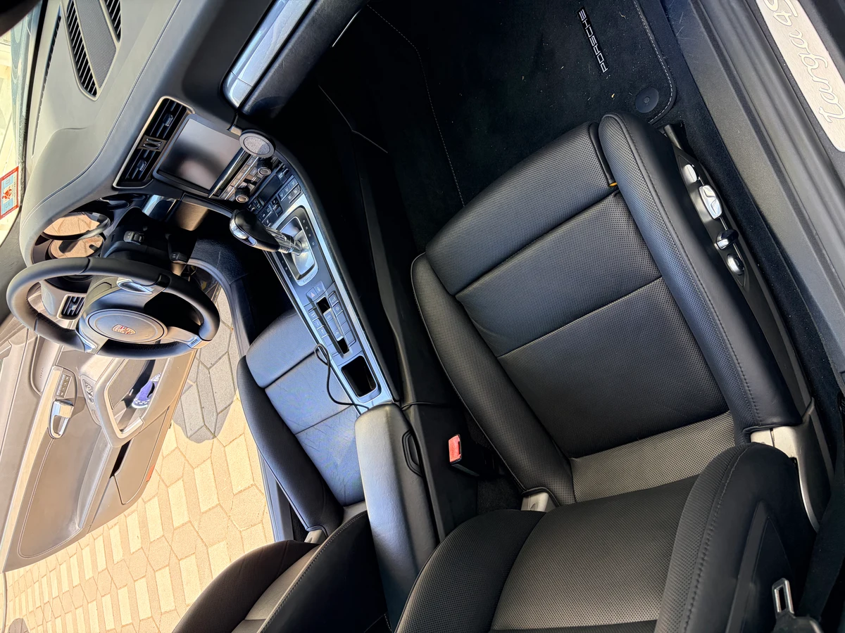 Porsche 911 Targa 4 interior after leather seat restoration — both front seats showing uniform black leather, steering wheel and center console visible