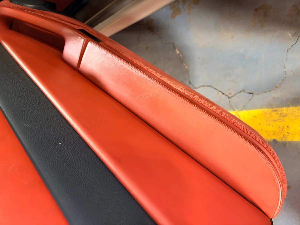 Porsche 993 door panel armrest after restoration — surface restored along seam edge, consistent orange-red color, clean profile
