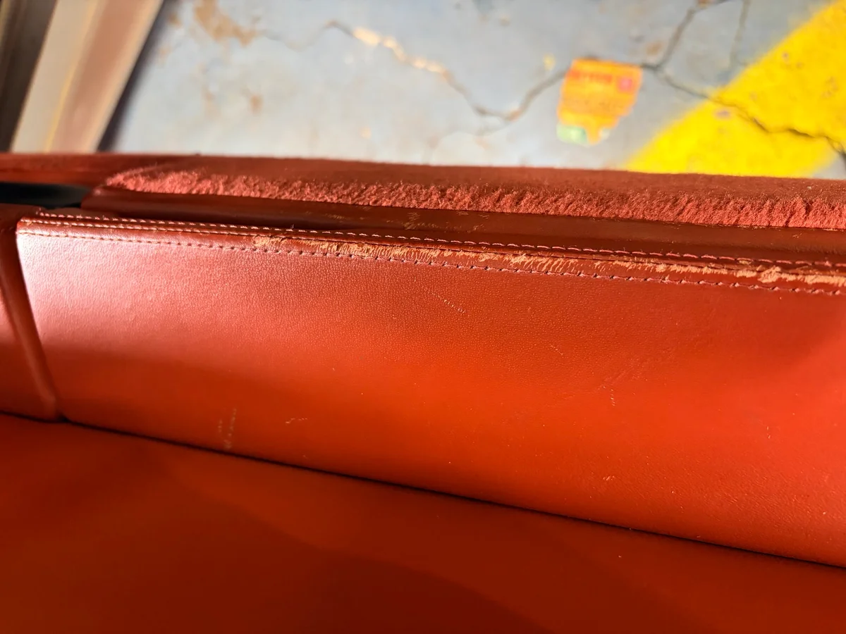 Porsche 993 door panel armrest before restoration — leather deteriorated and breaking down along the upper seam edge with finish loss