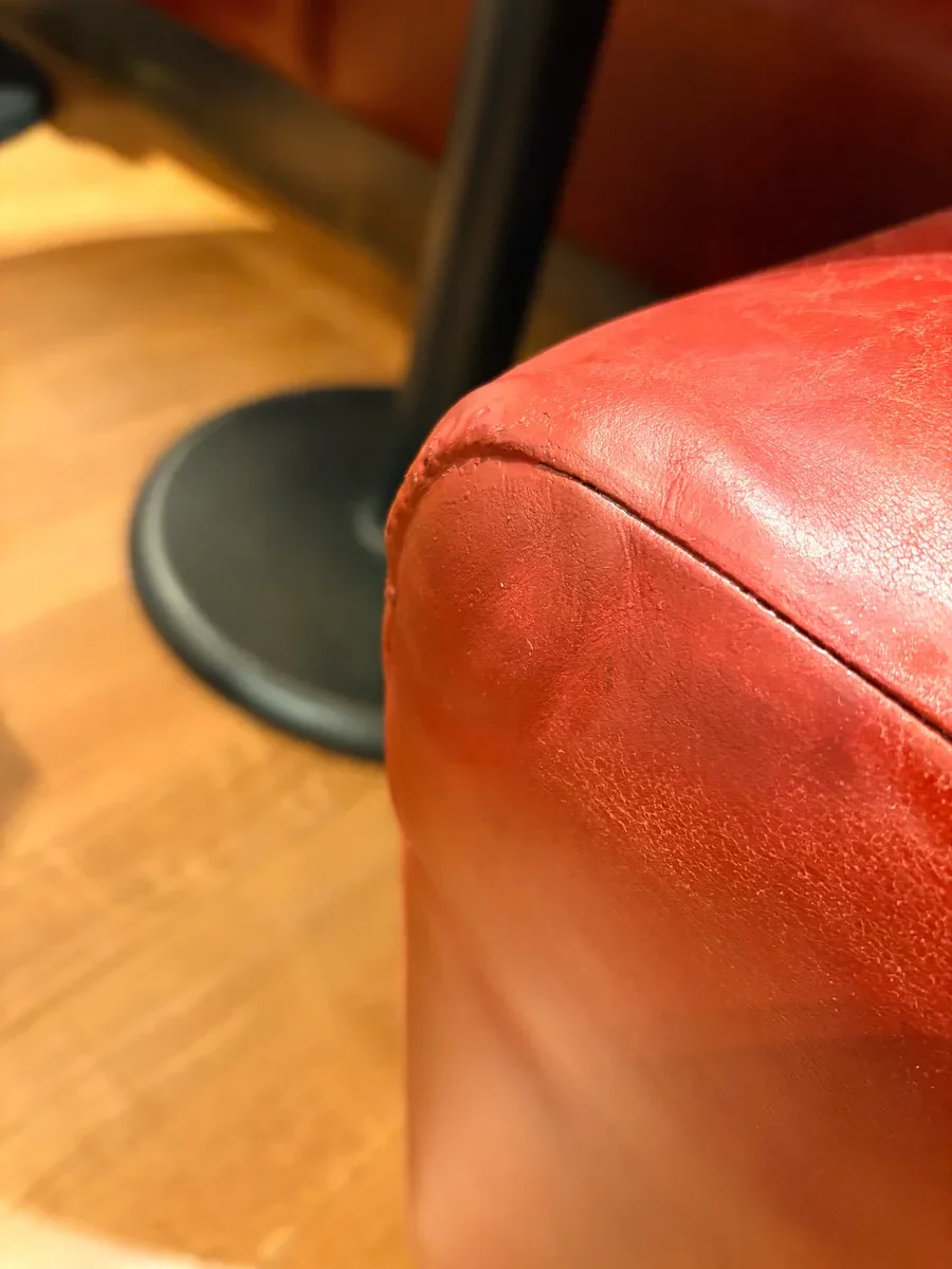 Repaired restaurant booth corner in Midtown Manhattan — smooth burgundy leather with the seam finished cleanly, no visible damage