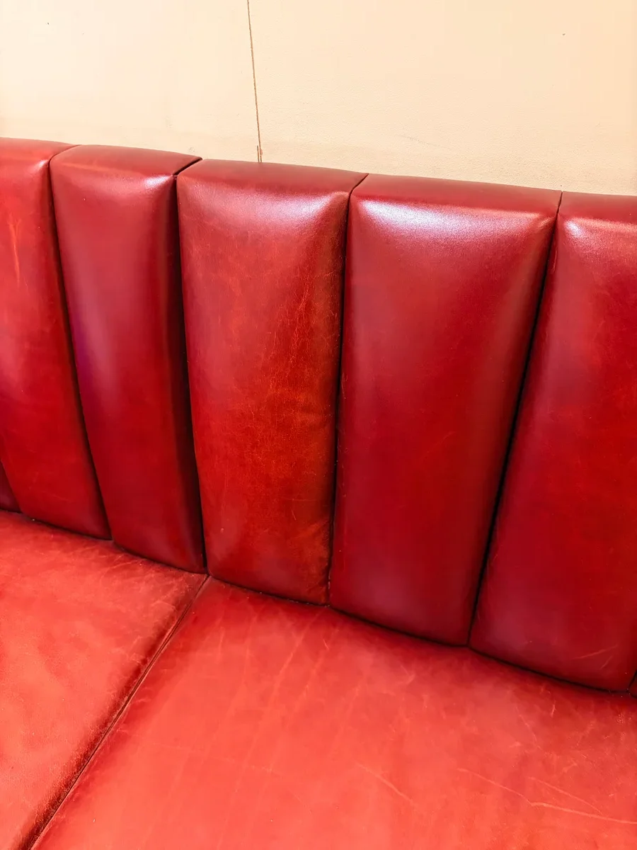 Restaurant leather banquette in Midtown Manhattan after commercial booth repair — deep burgundy leather restored with no visible seams, corners, or repair