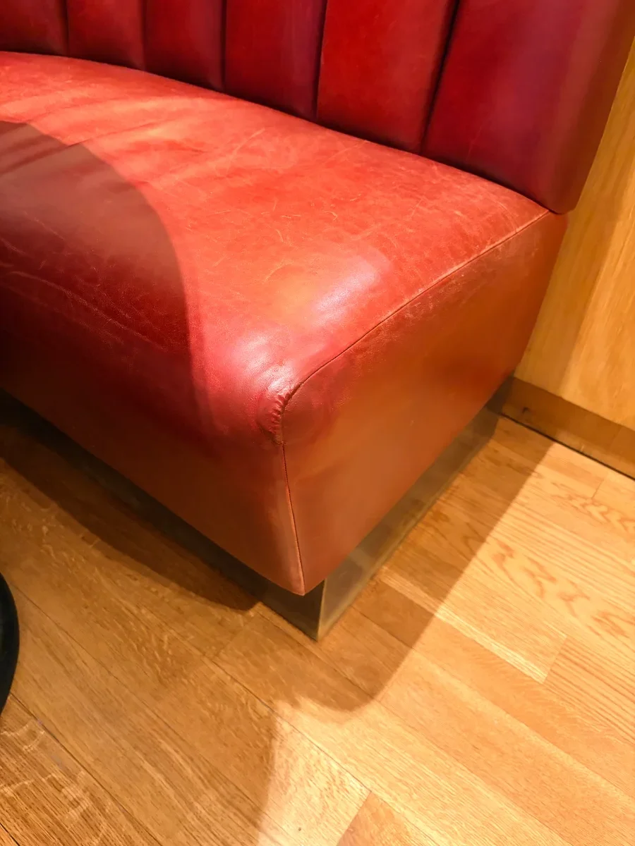 Restored restaurant leather booth corner in Midtown Manhattan — clean, undamaged burgundy leather at the seat/side transition after repair