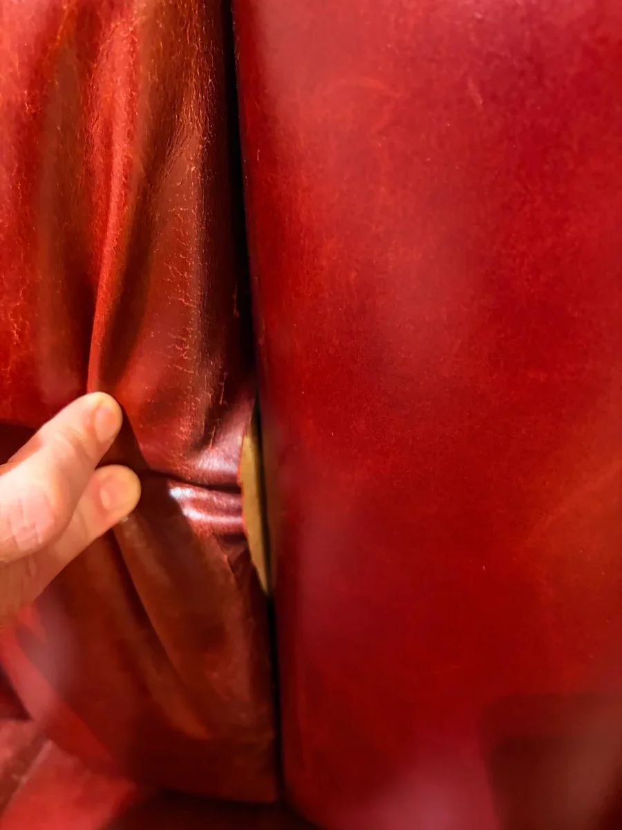 Leather & Vinyl Care technician inspecting a separated seam on a restaurant leather booth in Midtown Manhattan before fiber binder saturation and hand stitching