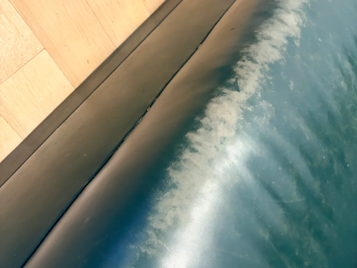 Teal leather sofa armrest before restoration — severe white discoloration and finish breakdown