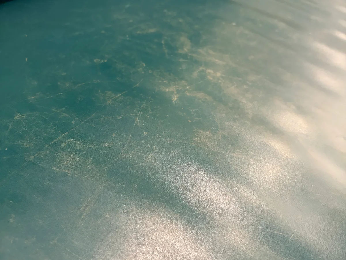 Teal leather sofa seat area before restoration — surface scratches and general wear