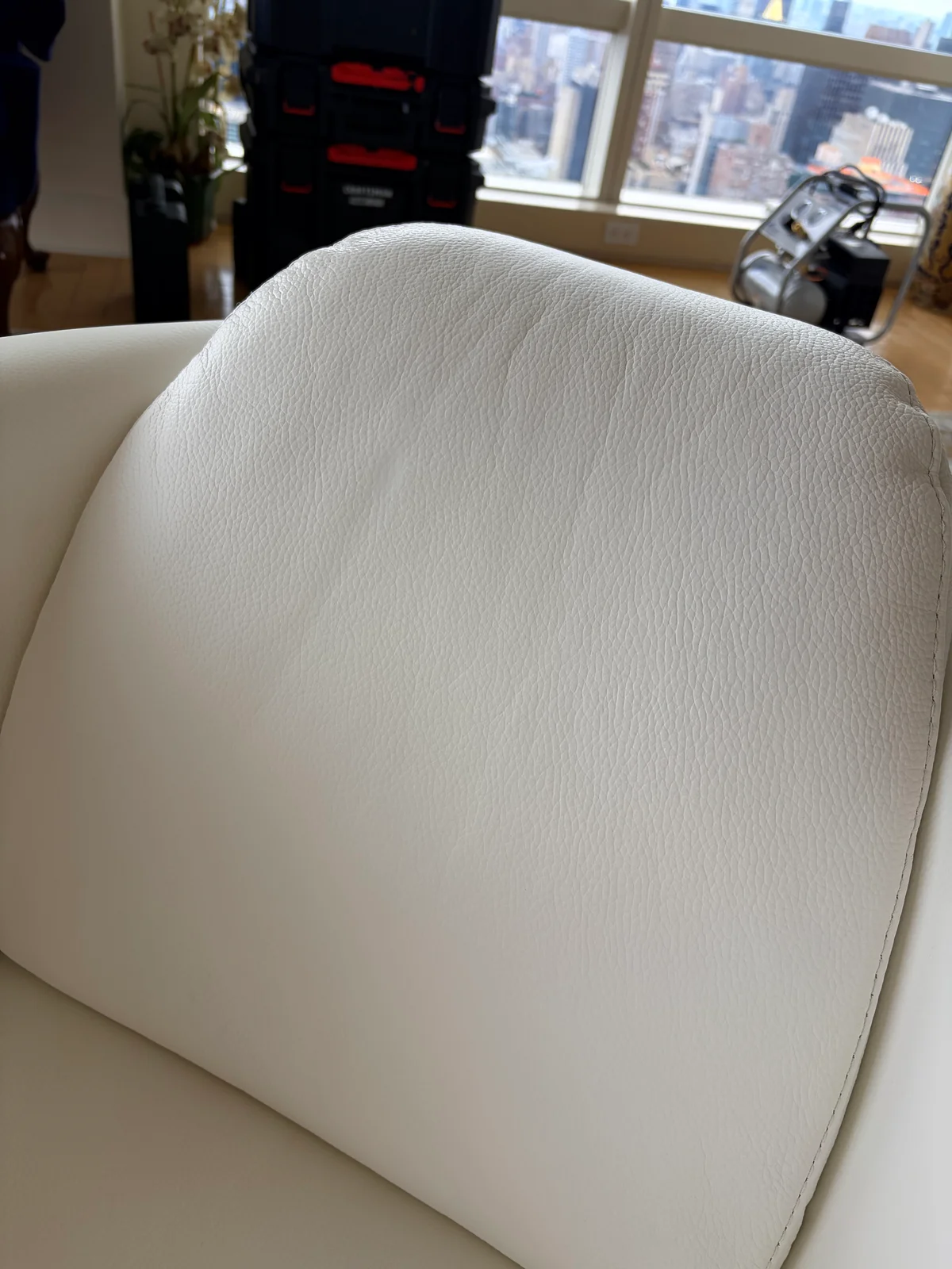 White leather chair backrest after restoration, clean and color matched with visible leather grain preserved