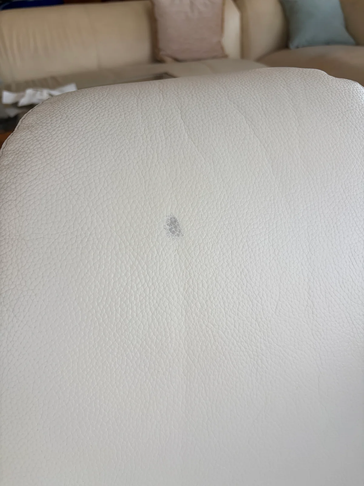 Second area of hair-dye discoloration on the headrest of a white leather lounge chair before restoration
